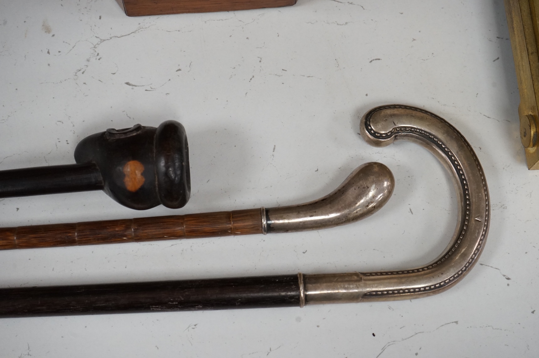 Two silver mounted walking sticks and a tribal carved ebony walking stick, longest 93cm